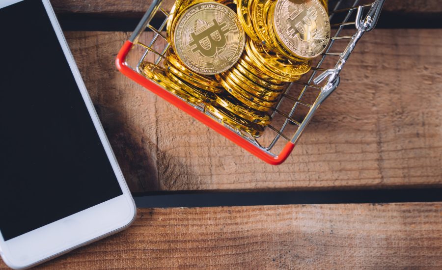 Basket of Crypto currency Bitcoin with smart phone over wooden background
